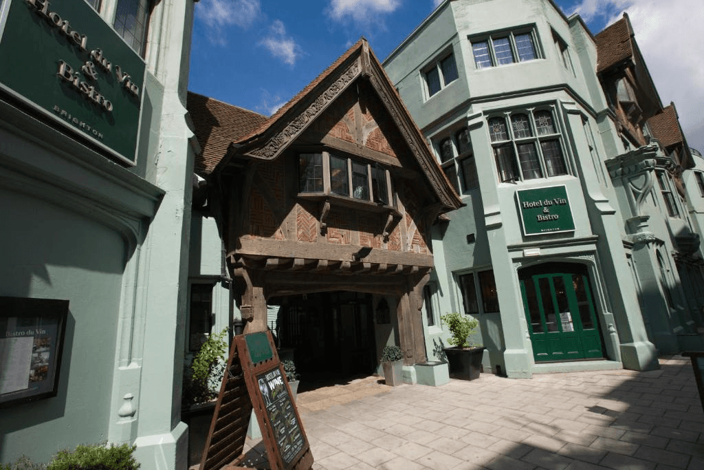 Exterior of Hotel du Vin Brighton showing a timber-framed entrance between pale green buildings.