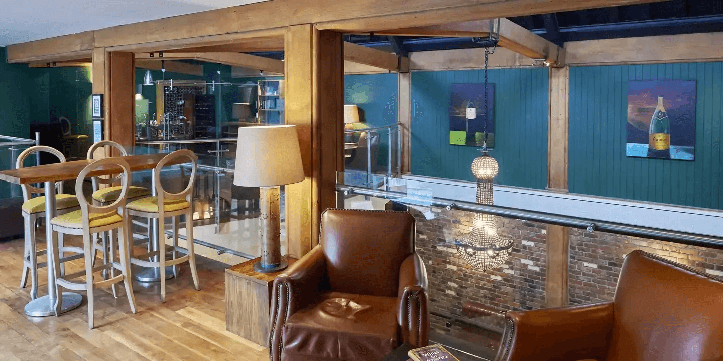 Leather armchairs and bar stools in a warmly lit lounge with exposed brickwork.