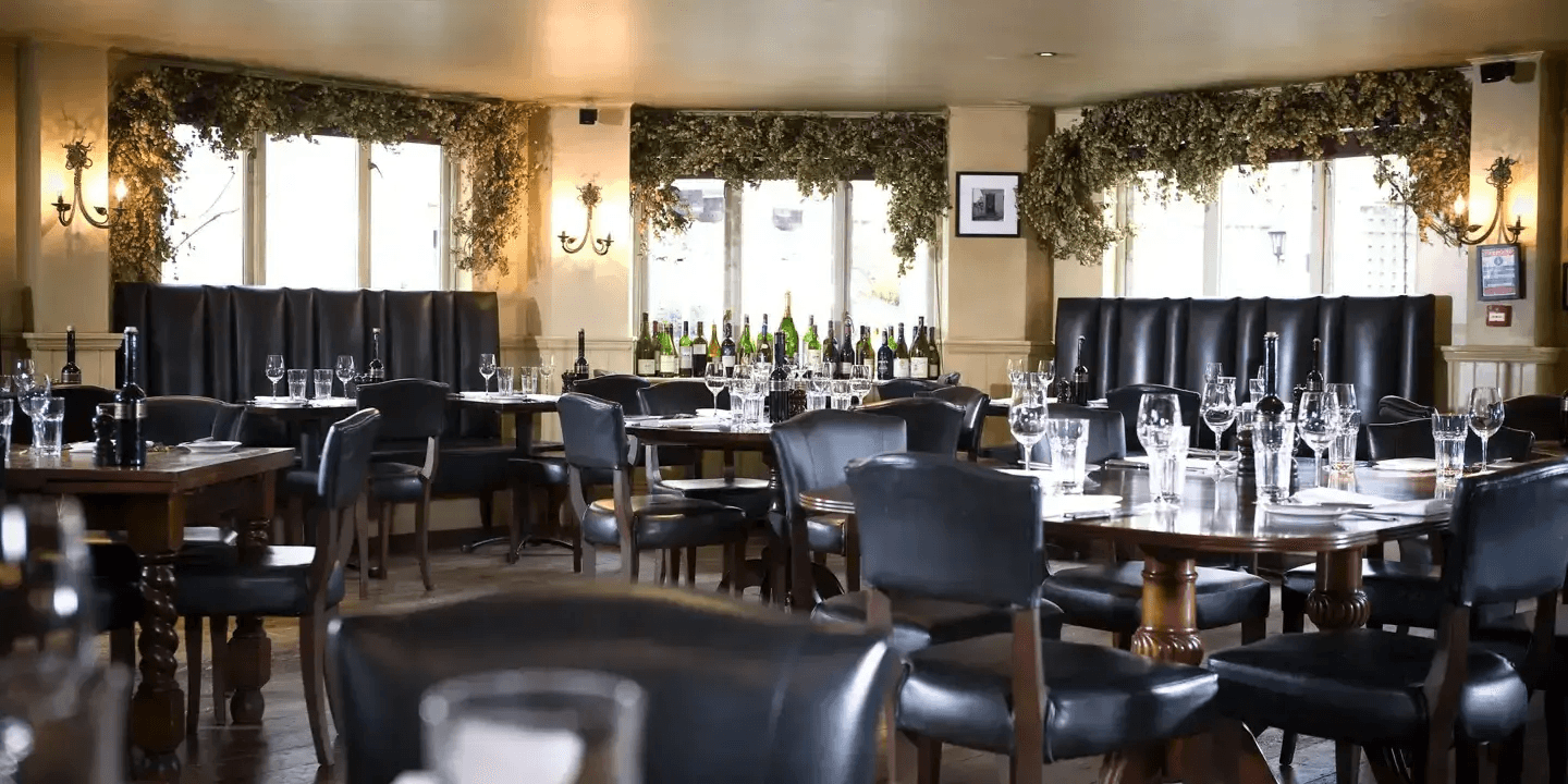 The restaurant dining room with dark leather chairs, wooden tables and dried hop garlands.