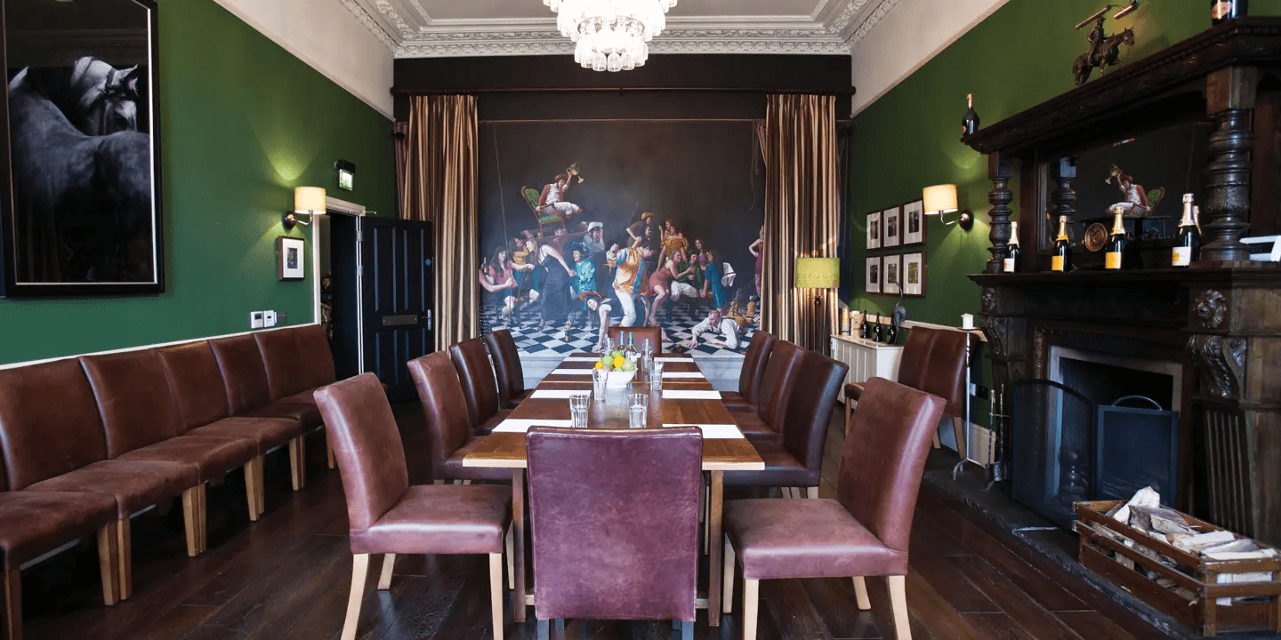 Private dining room with long wooden table, leather chairs and bold artwork.