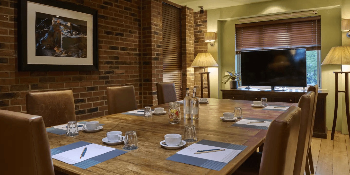 Private dining room with a rustic wooden table, leather chairs and exposed brick walls.