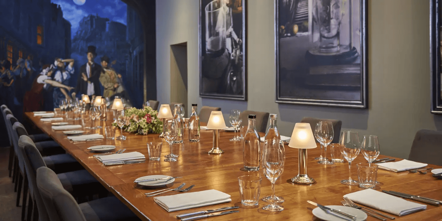 Private dining room with a long wooden table set for a formal dinner, artworks on walls.