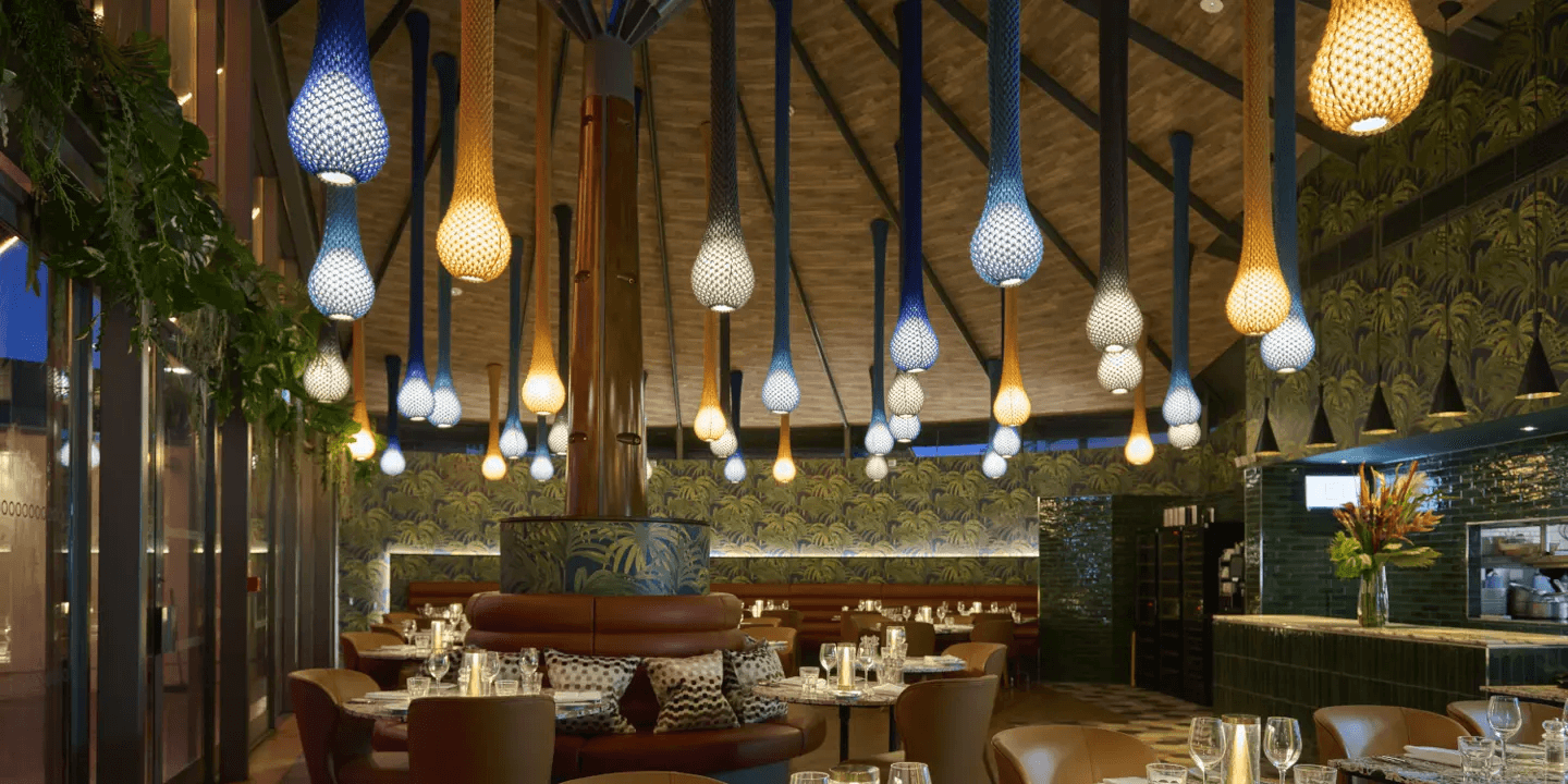 Restaurant interior at Hotel du Vin Exeter with colourful teardrop pendant lights and tropical wallpaper.