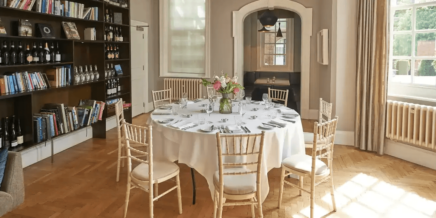 Private dining room with a round laid table, chiavari chairs and bookshelves at Hotel du Vin Exeter.