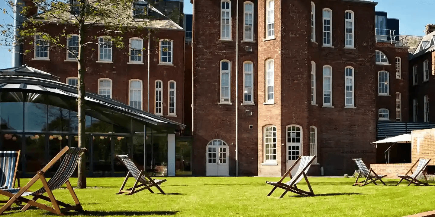 Striped deckchairs on the lawn outside Hotel du Vin Exeter's red brick building.