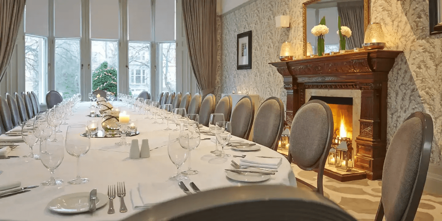 Private dining room with long laid table, lit fireplace and garden views at Hotel du Vin Glasgow.
