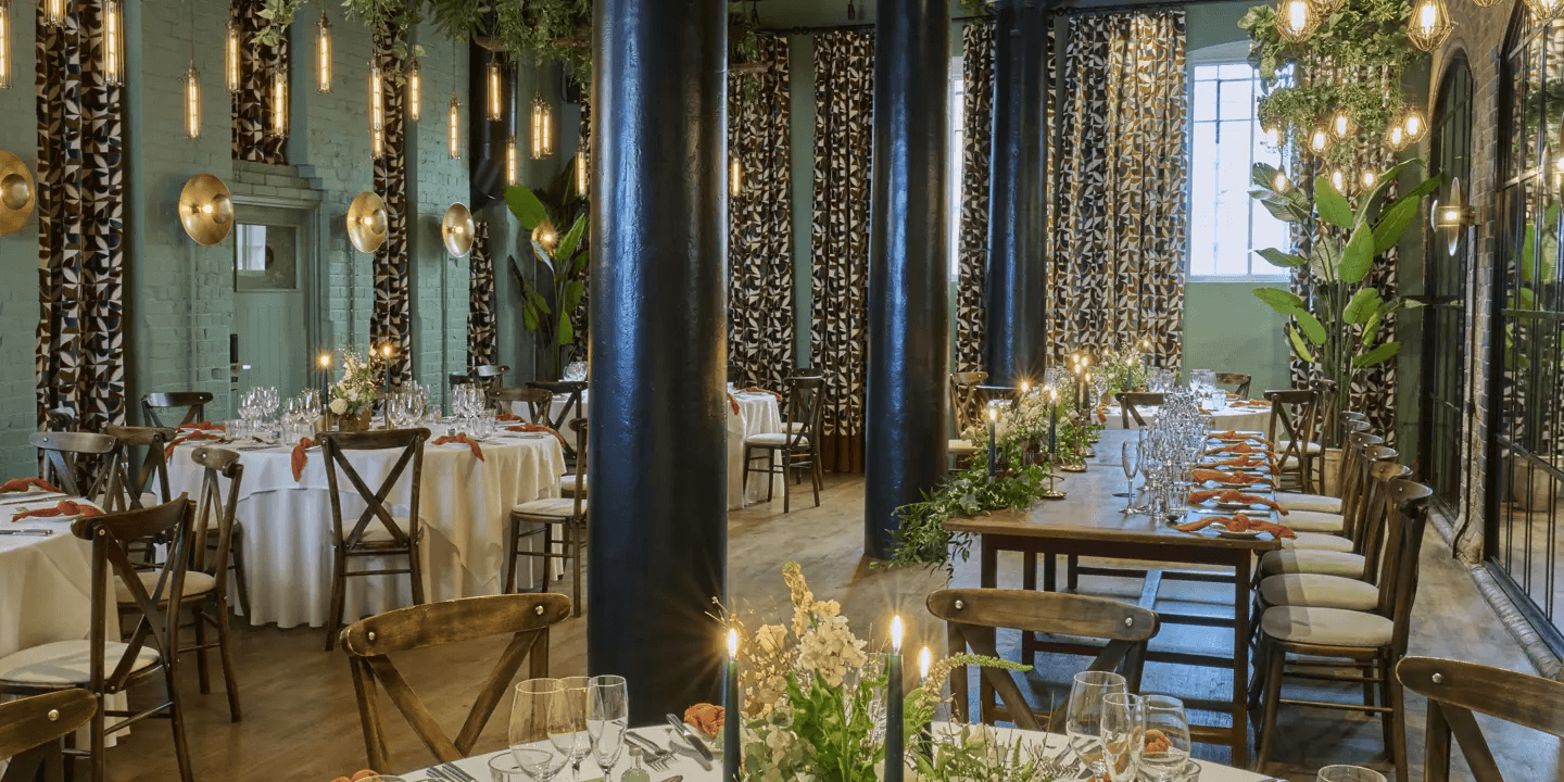Private dining room with round and long tables set for a formal event with candles and greenery.