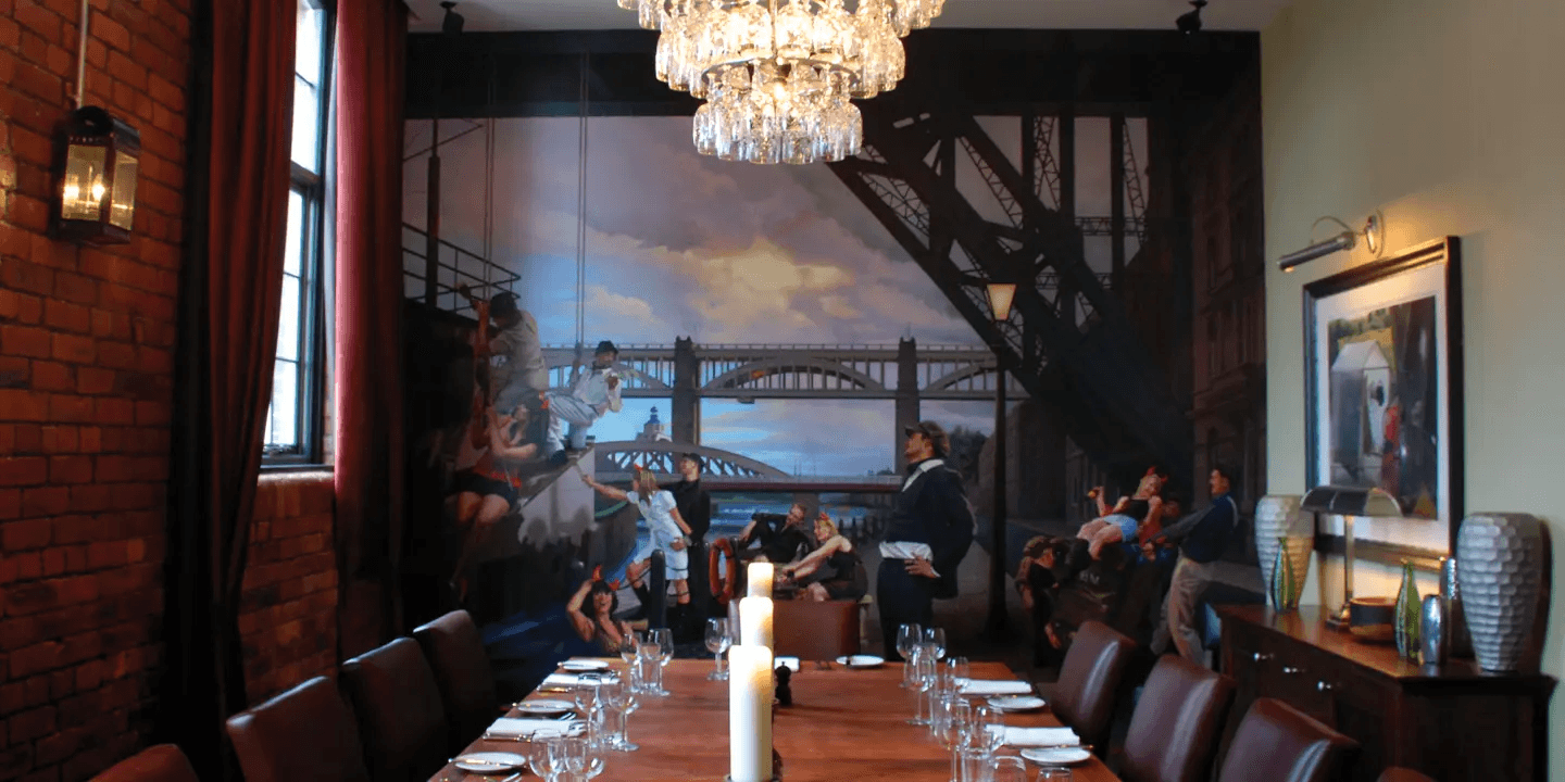 Private dining room with long table, chandelier and Tyne Bridge mural