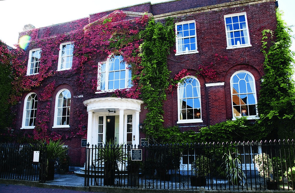 Red brick Georgian exterior of Hotel du Vin Poole covered in vivid autumn ivy.