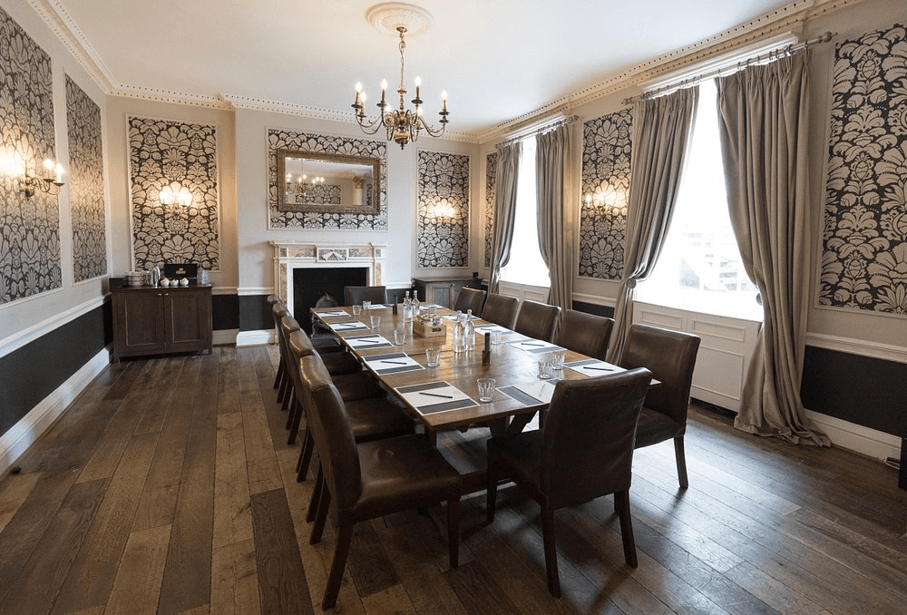 Boardroom with a long dining table, leather chairs and patterned wallpaper at Hotel du Vin Poole.