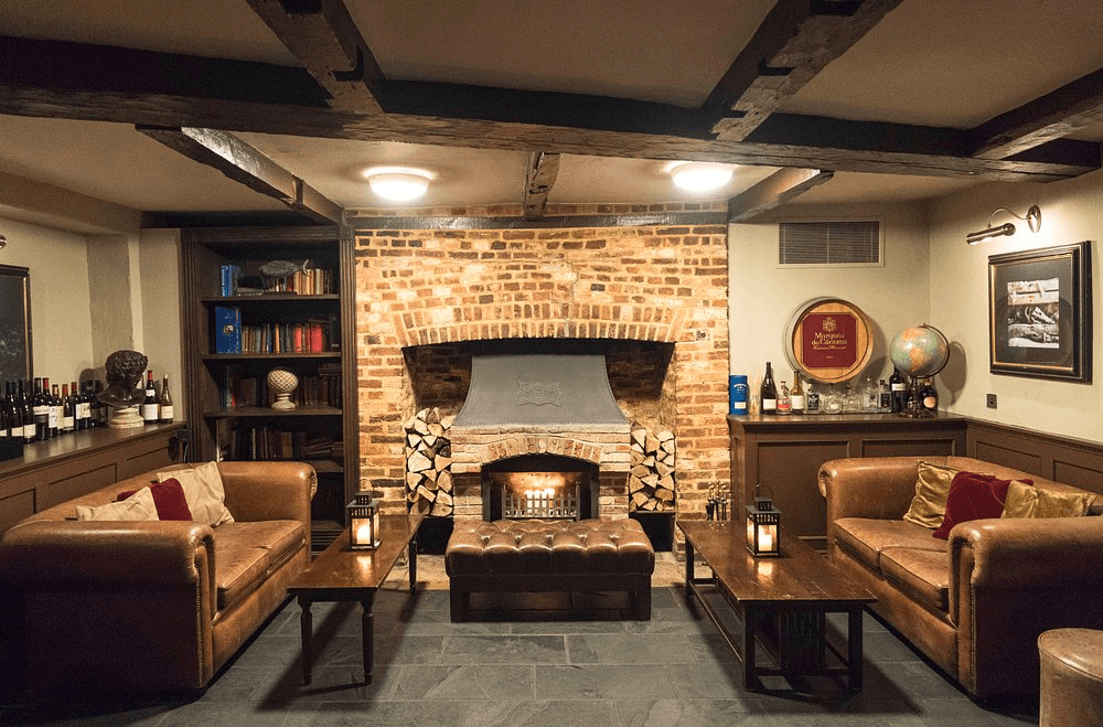 Cosy lounge bar with lit fireplace, leather sofas and exposed brick surround.