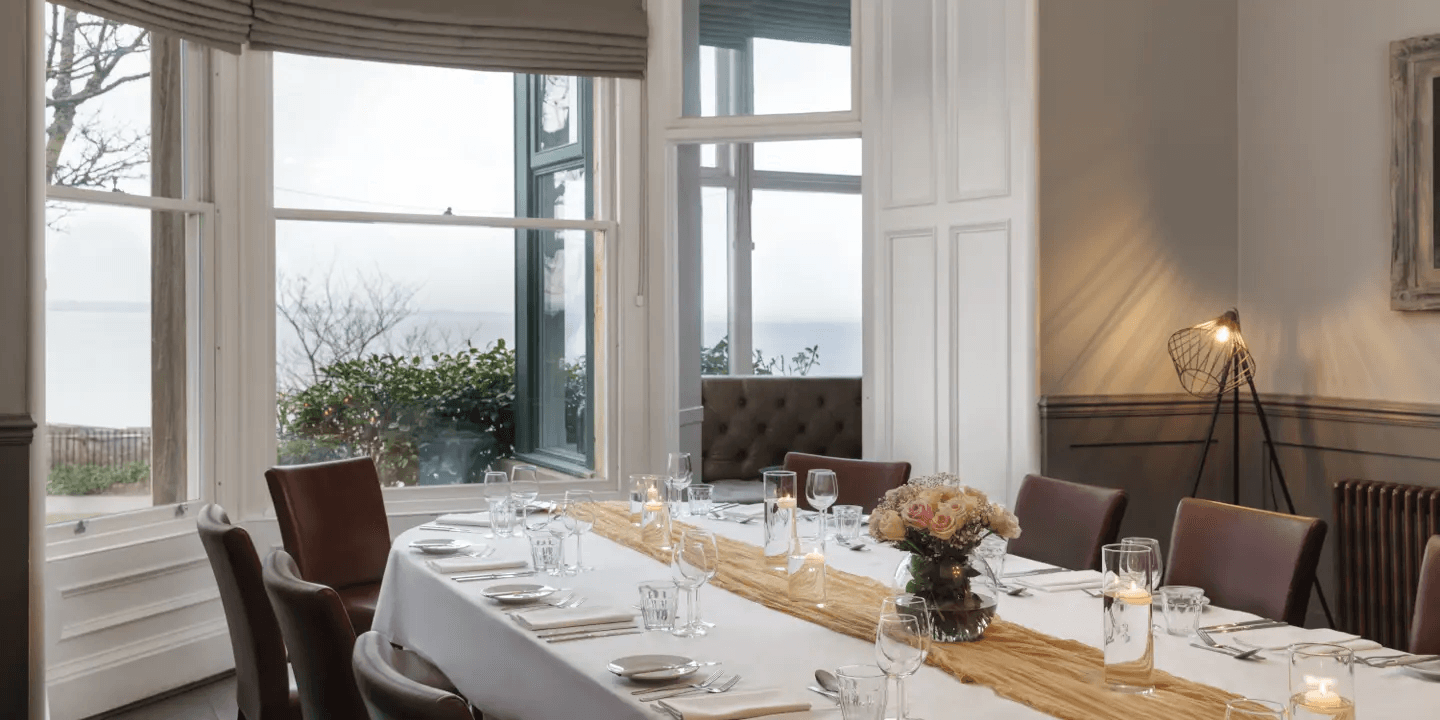 Private dining room with a laid table, sea views and a floor lamp.