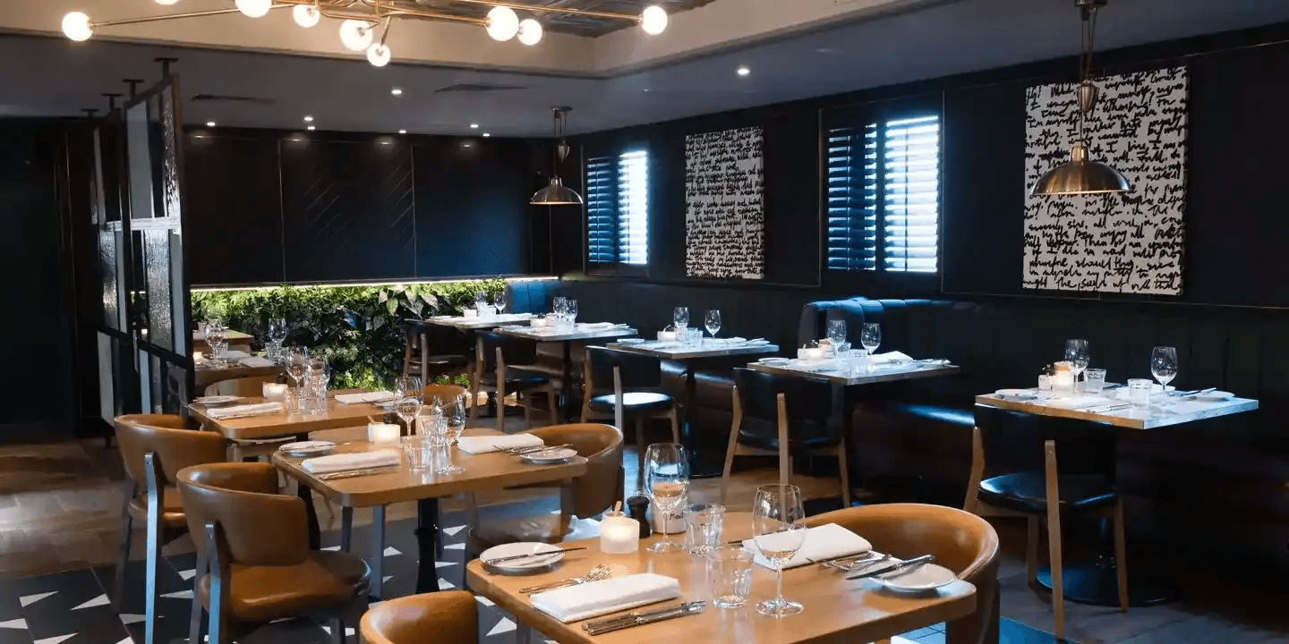 Elegantly laid restaurant dining room with tan leather chairs and dark walls at Hotel du Vin Stratford-upon-Avon.