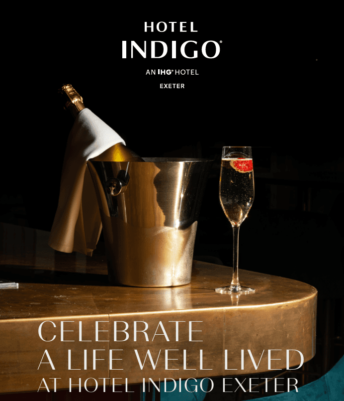 Champagne bottle in ice bucket beside a filled flute on a polished bar top.