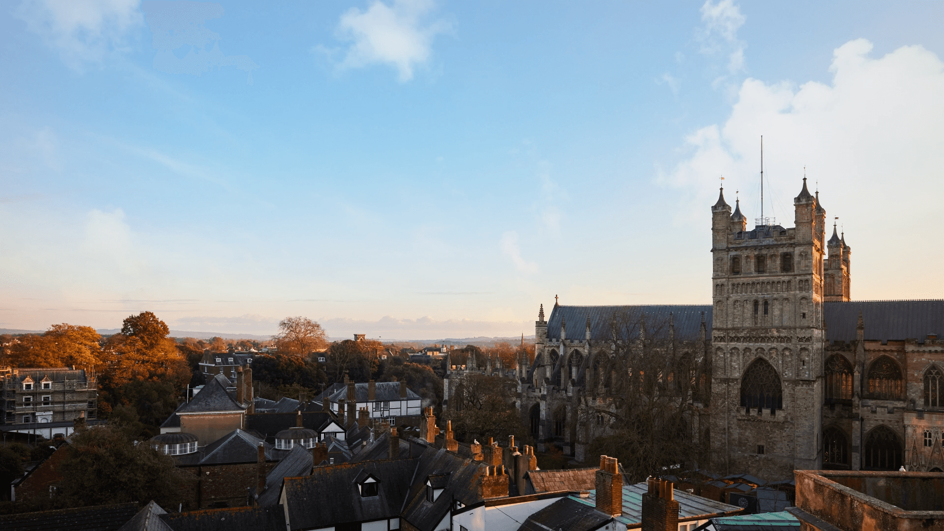 Rooftop view over Exeter city centre with the cathedral tower at golden hour.