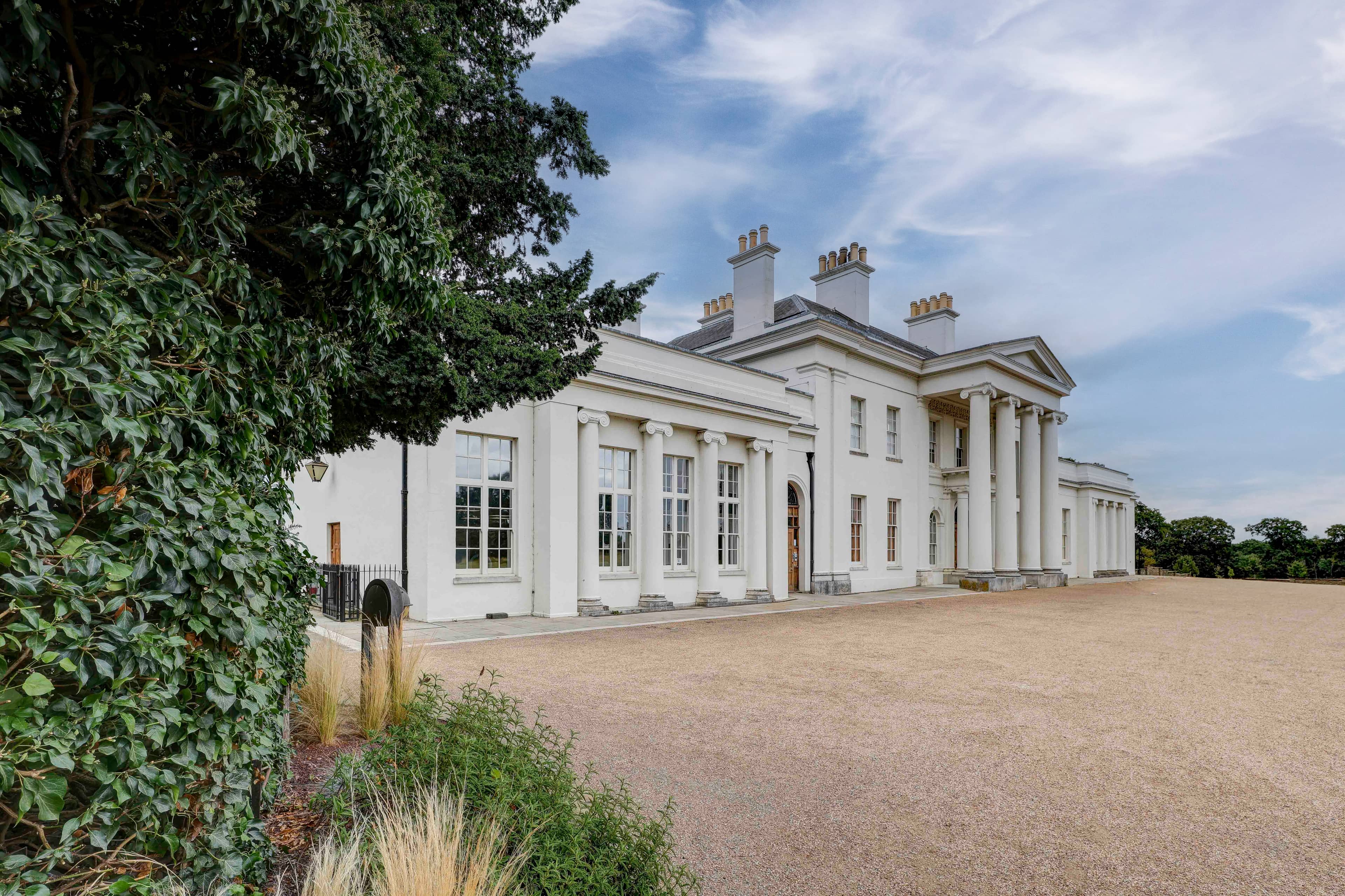 The white neoclassical exterior of Hylands Estate set against a gravel forecourt.