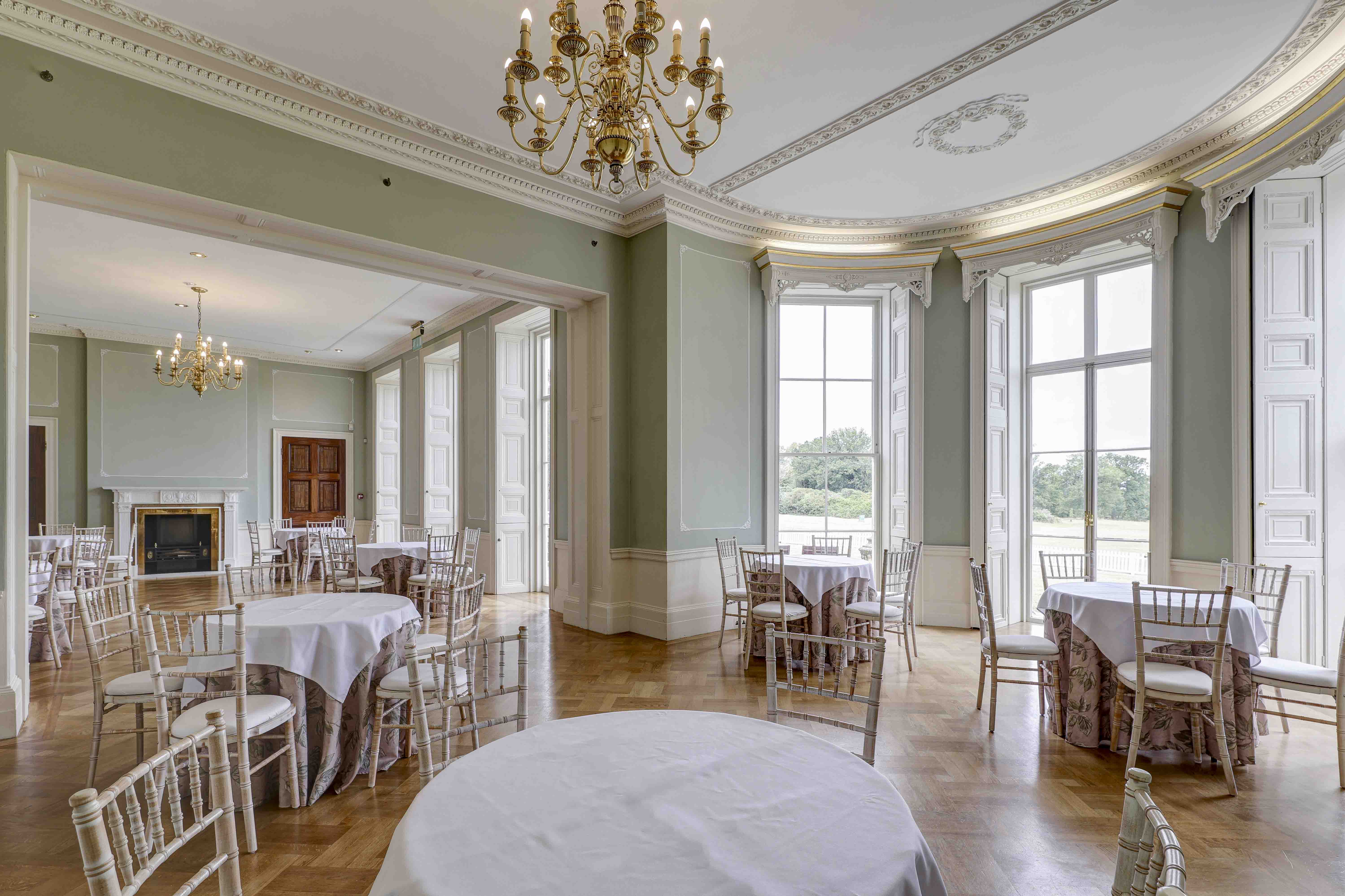 Georgian function room at Hylands Estate with round tables, chiavari chairs and tall sash windows.