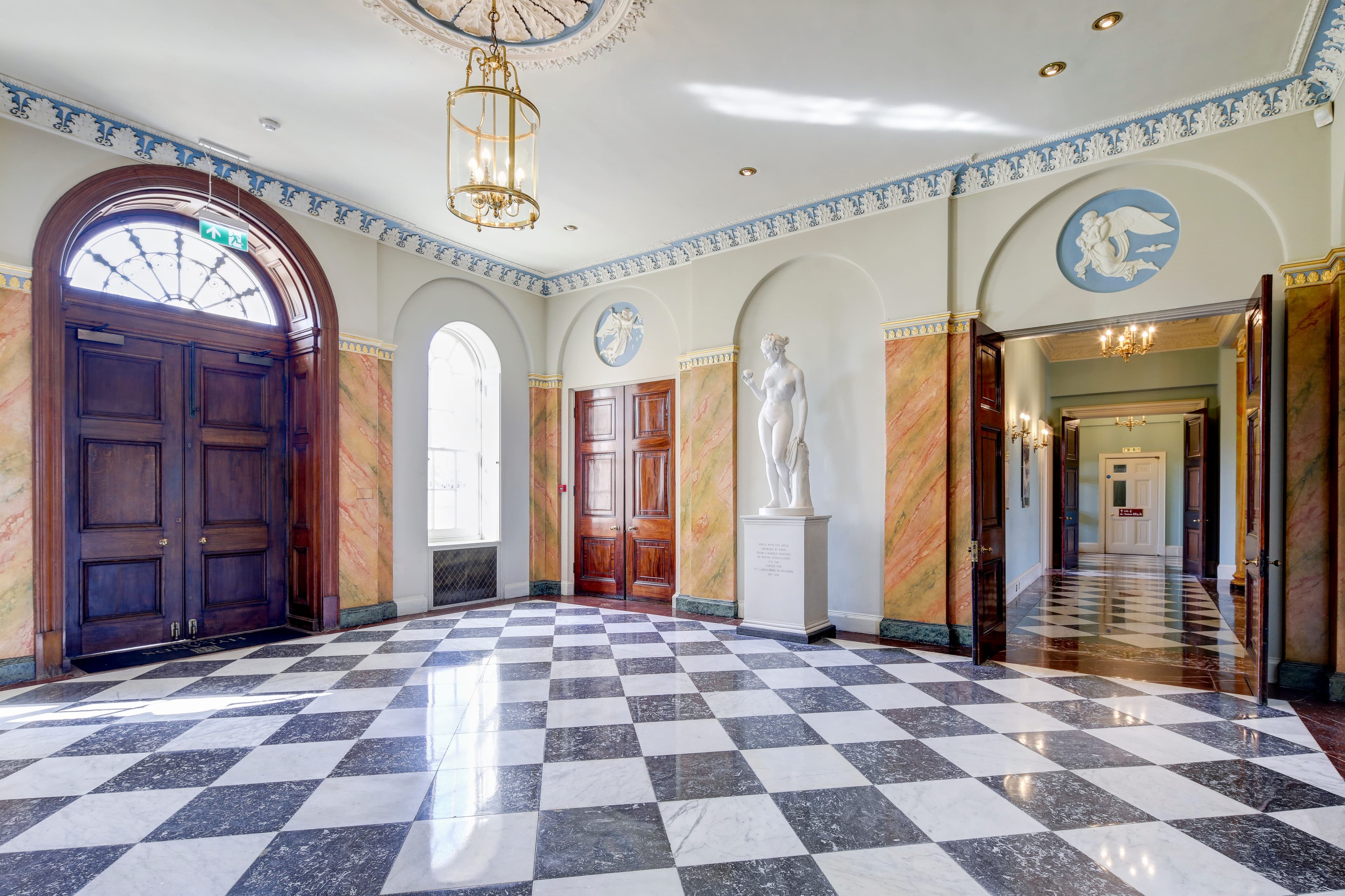 Grand entrance hall with chequered marble floor, classical statue and ornate plasterwork at Hylands Estate.