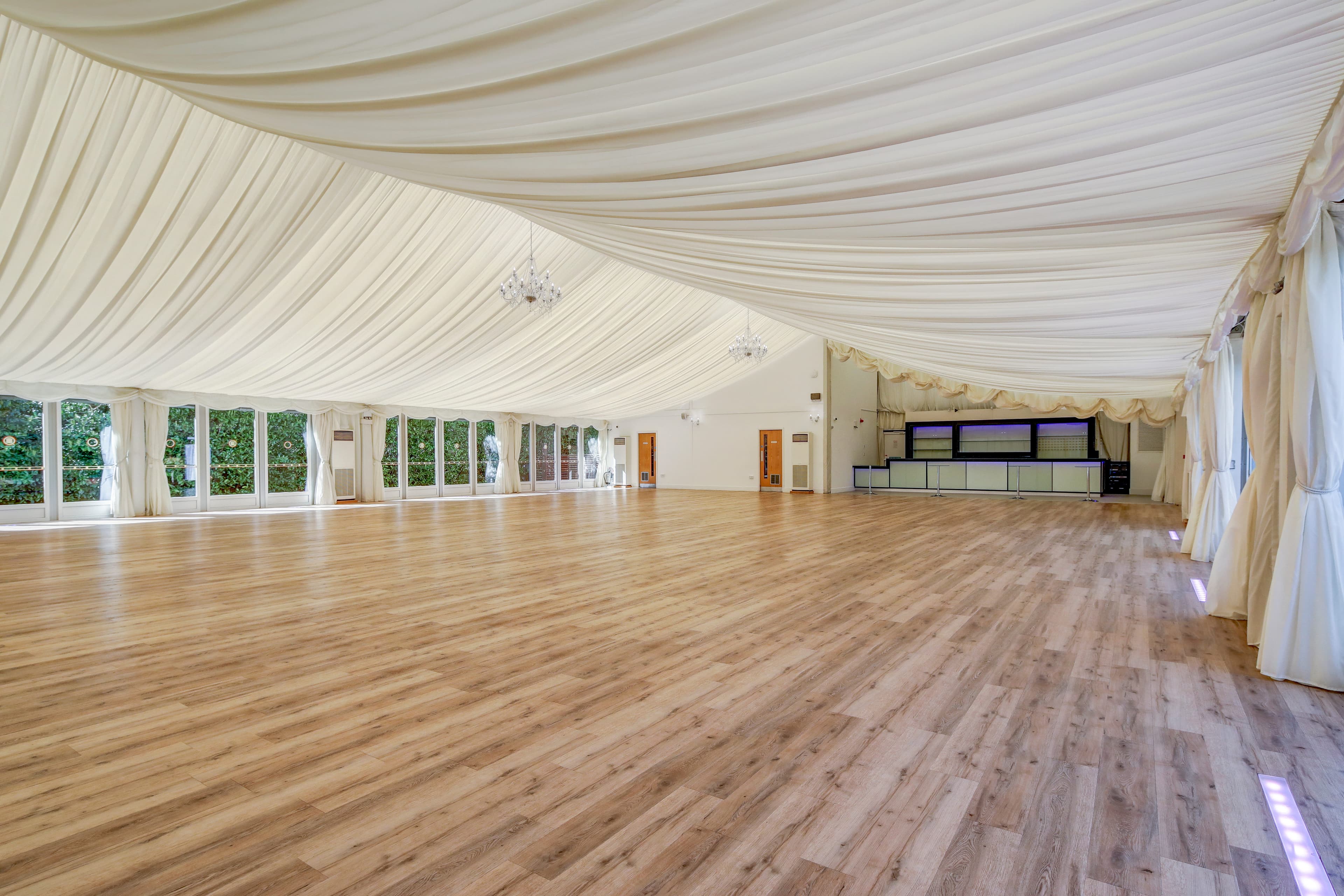 Empty marquee interior at Hylands Estate with draped ceiling, chandeliers and wood floor.