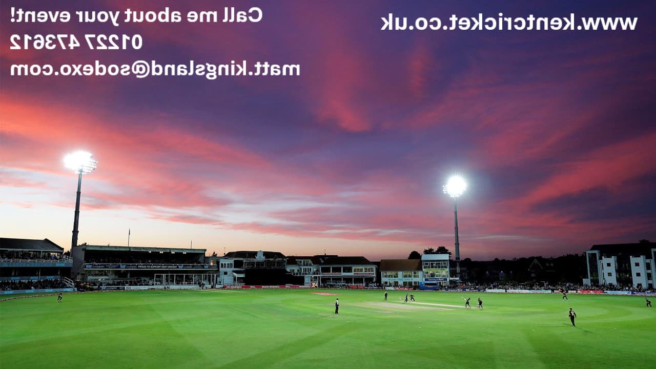 St Lawrence Ground cricket pitch under floodlights at dusk with a vivid pink sky.