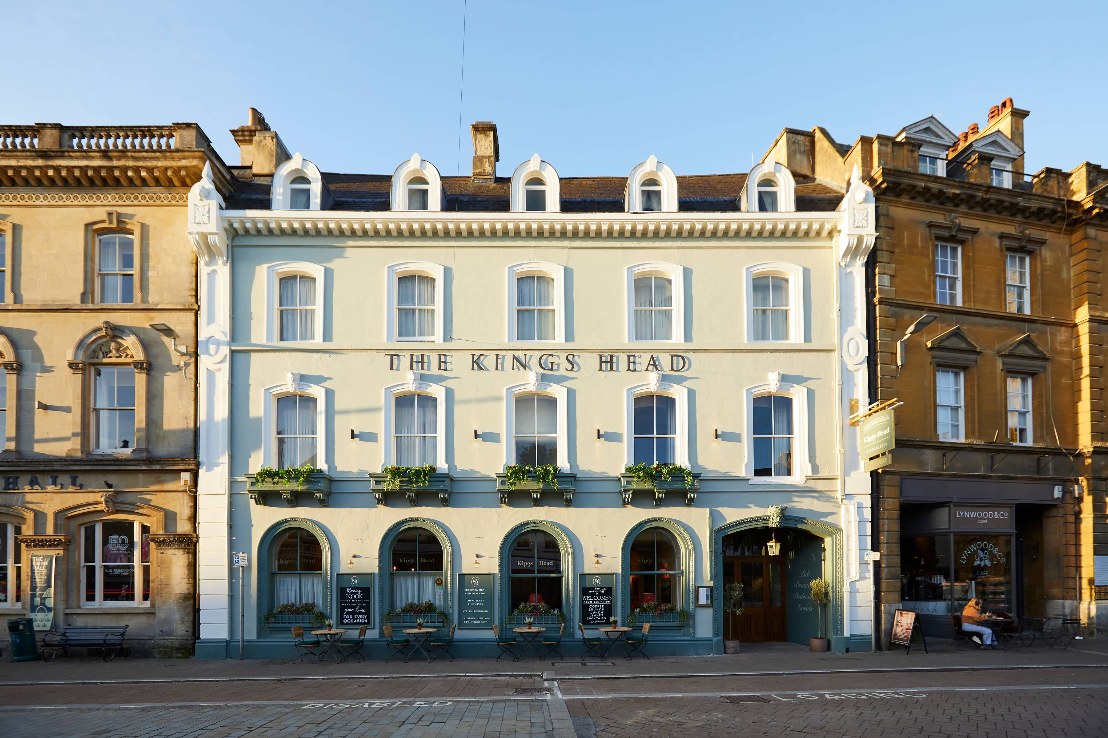The pale rendered exterior of The Kings Head pub in Cirencester town centre.