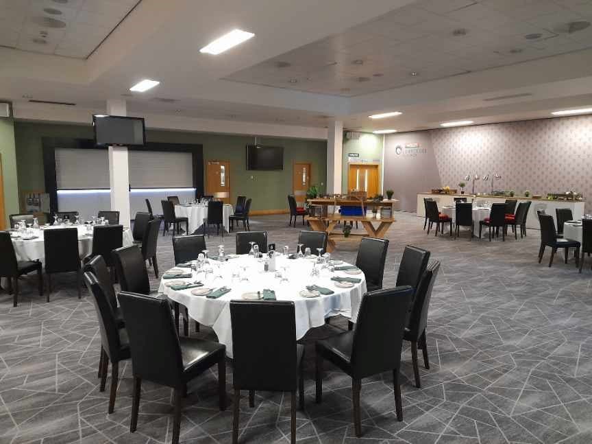 Function room with round tables set for dining and a projector screen