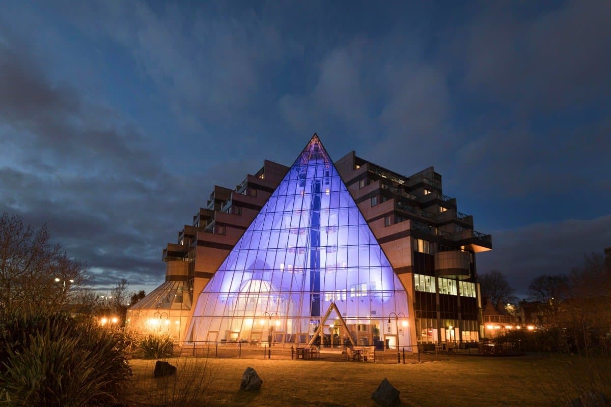 Illuminated triangular glass atrium on the exterior of a large hotel at dusk