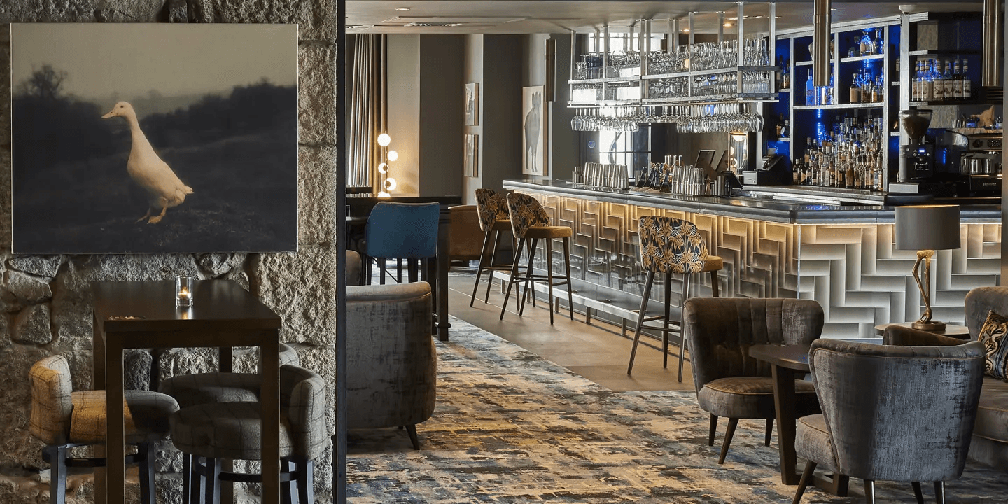 Stylish hotel bar with patterned upholstery, high stools and a well-stocked back bar.