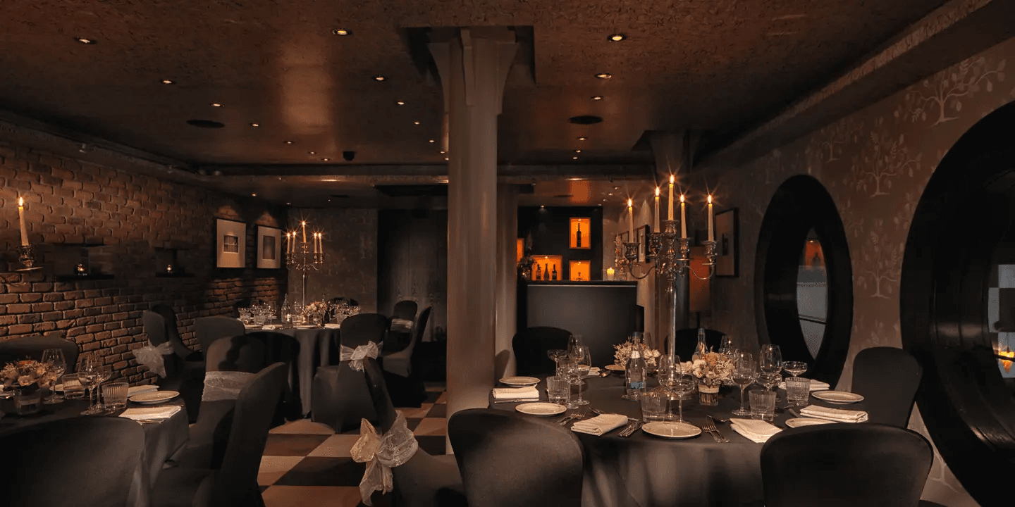 Candlelit private dining room with brick walls, dark chairs and laid tables at Malmaison Belfast.