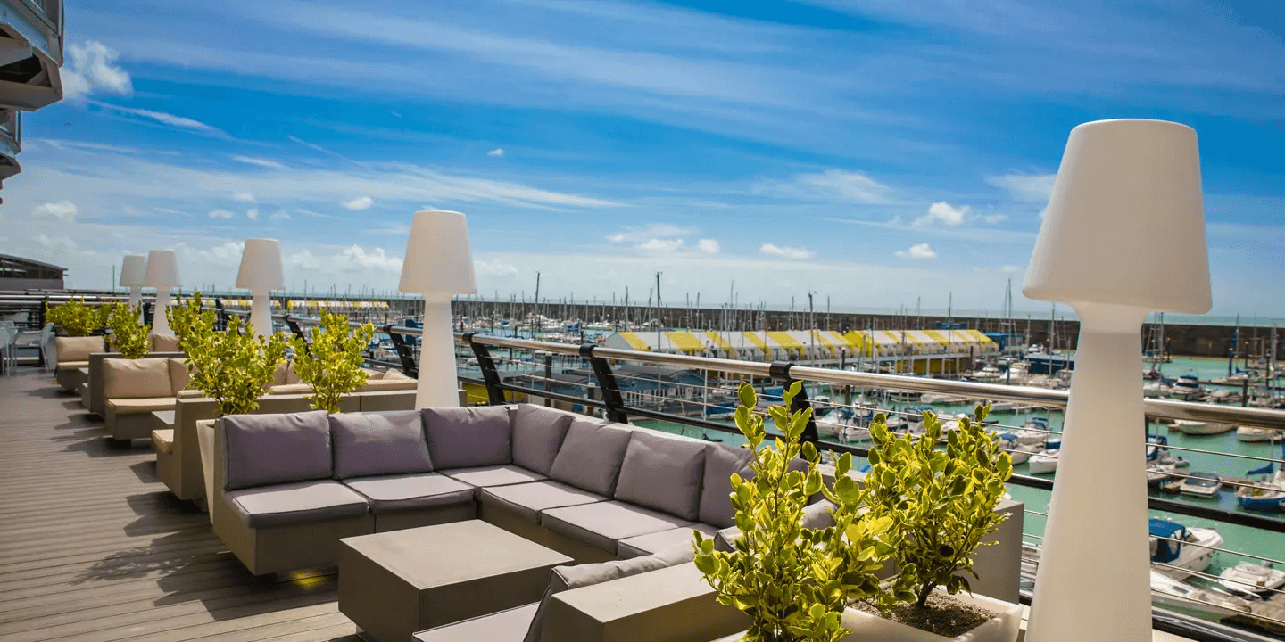 Rooftop terrace with modular seating and tall lamps overlooking Brighton Marina.