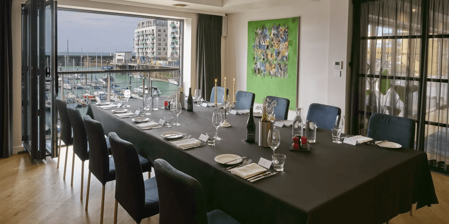 Private dining room with marina views, set long table and candles at Malmaison Brighton.