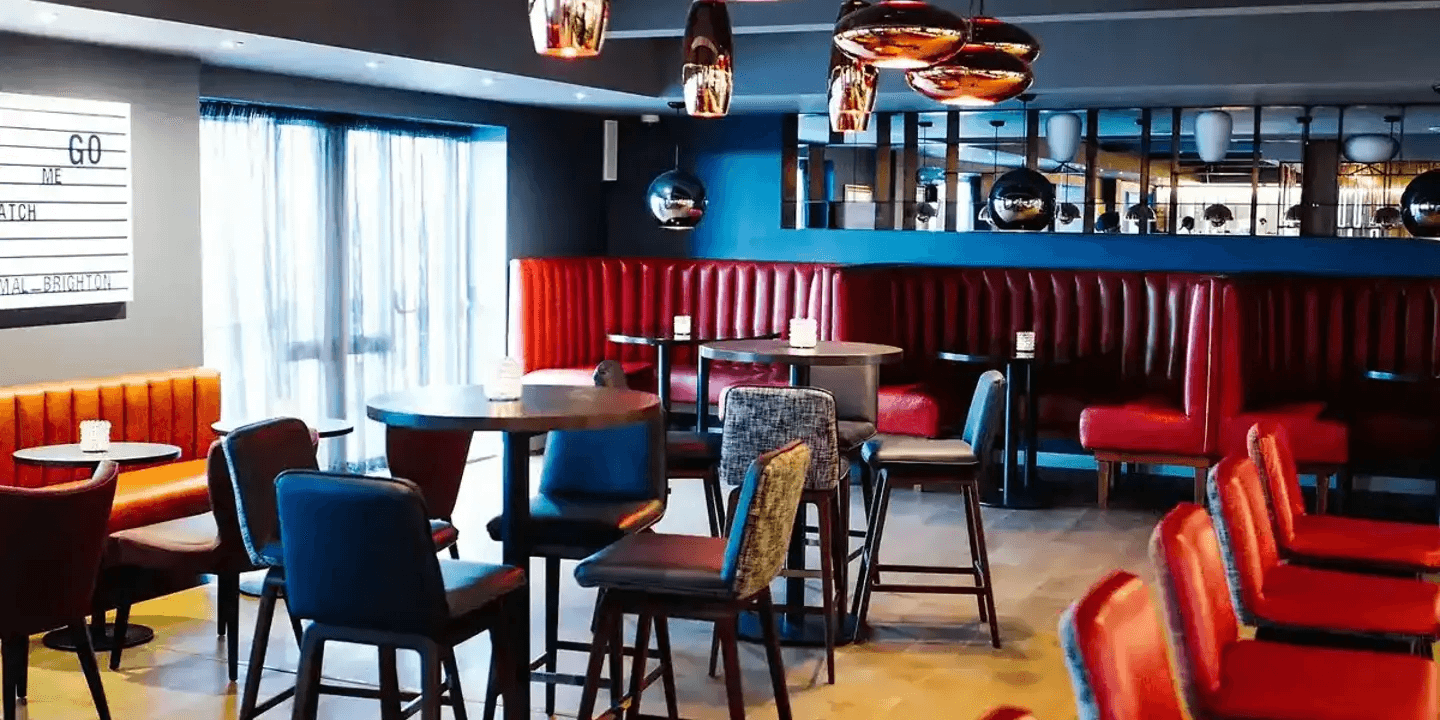 Bar and seating area with red leather booths, high tables and pendant lighting at Malmaison Brighton.