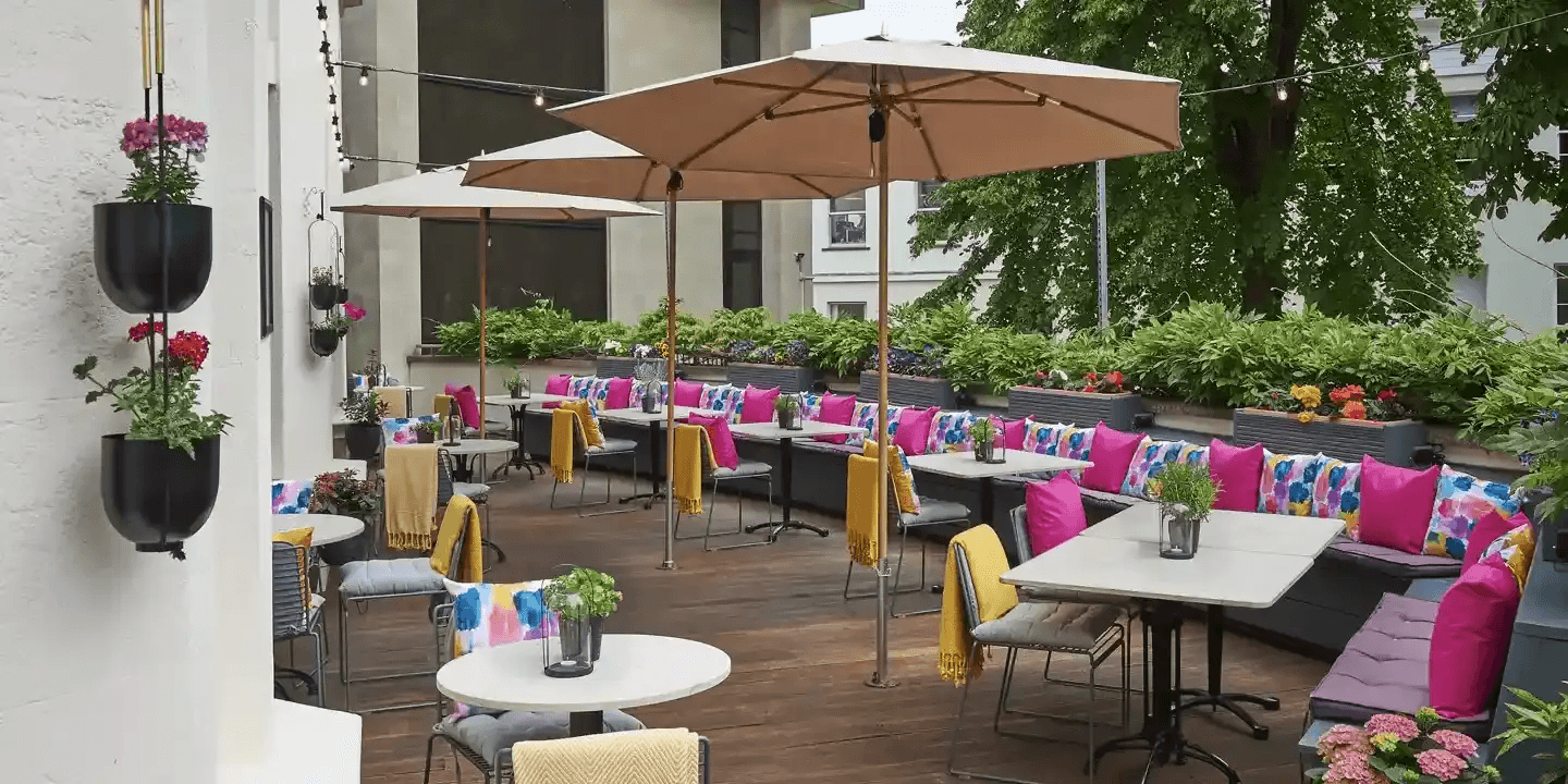 Outdoor terrace at Malmaison Cheltenham with bright cushions, parasols and planted borders.