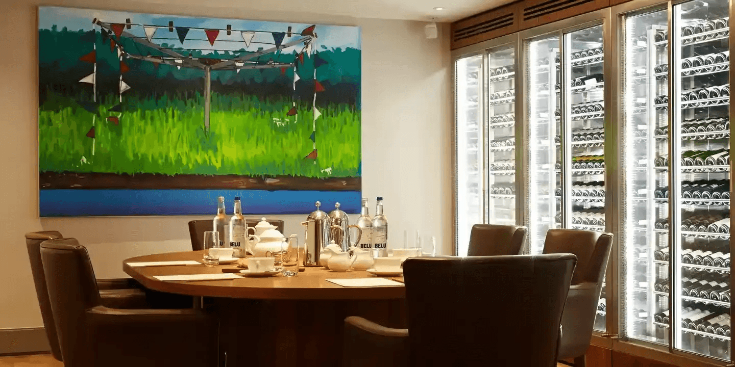Private dining room with round table, leather chairs and illuminated wine storage cabinets.