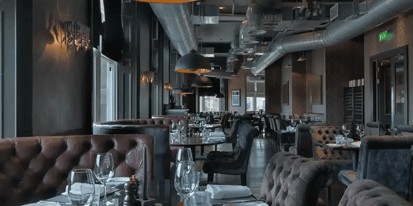 Dimly lit restaurant interior with button-back leather booths and laid tables at Malmaison Dundee.