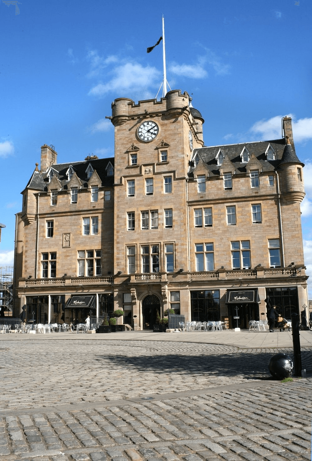 Sandstone exterior of Malmaison Edinburgh with clock tower and cobbled forecourt.