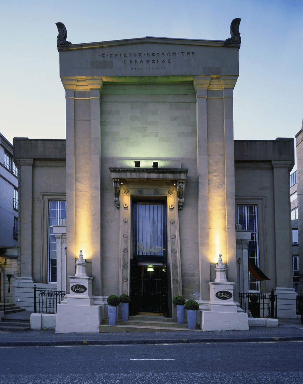 Floodlit stone facade of Malmaison Glasgow hotel at dusk with ornate entrance doorway