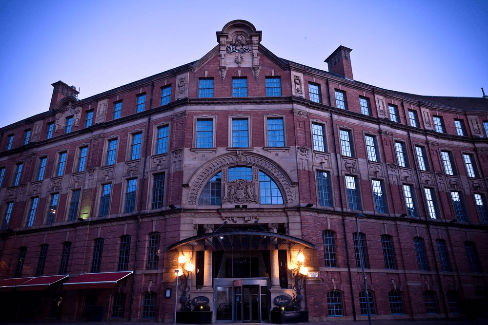 The red brick exterior of Malmaison Leeds hotel photographed at dusk from street level.