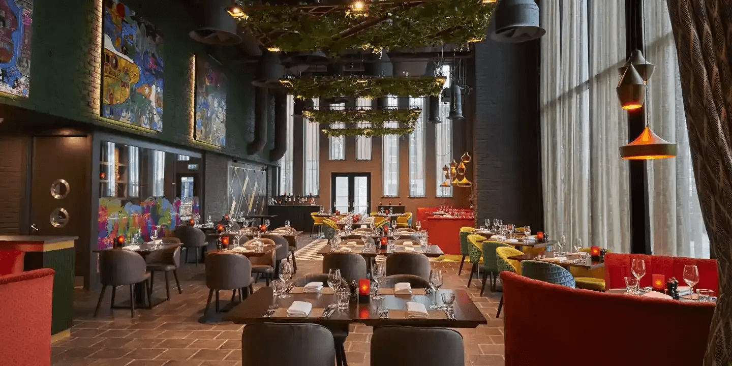 Restaurant dining room with trailing greenery ceiling installation and colourful wall murals at Malmaison Liverpool.