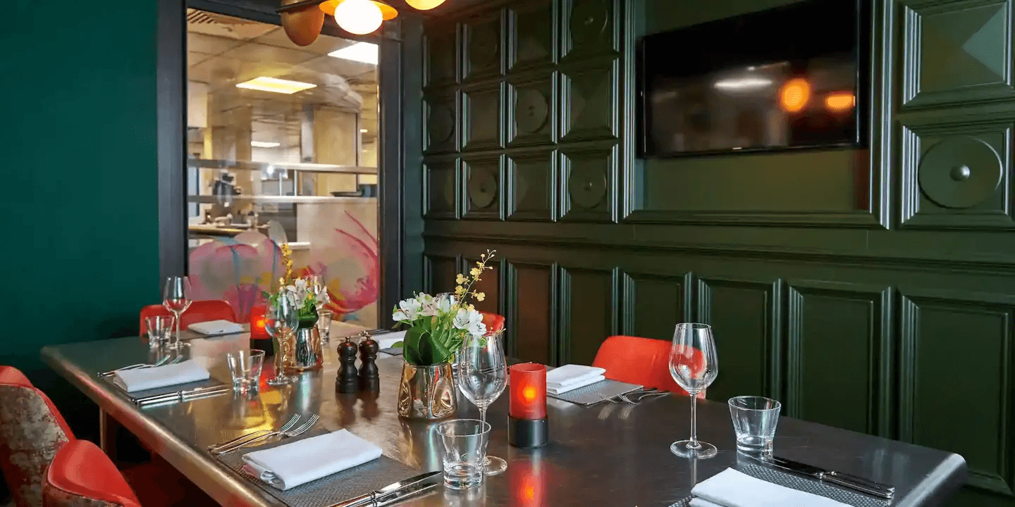 Private dining room at Malmaison Liverpool with dark green panelling and open kitchen view.
