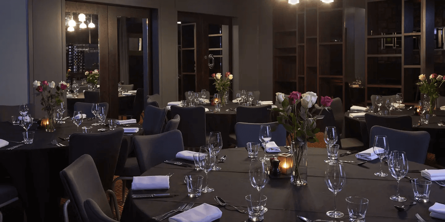 Private dining room at Malmaison London set with round tables, glassware and rose centrepieces.