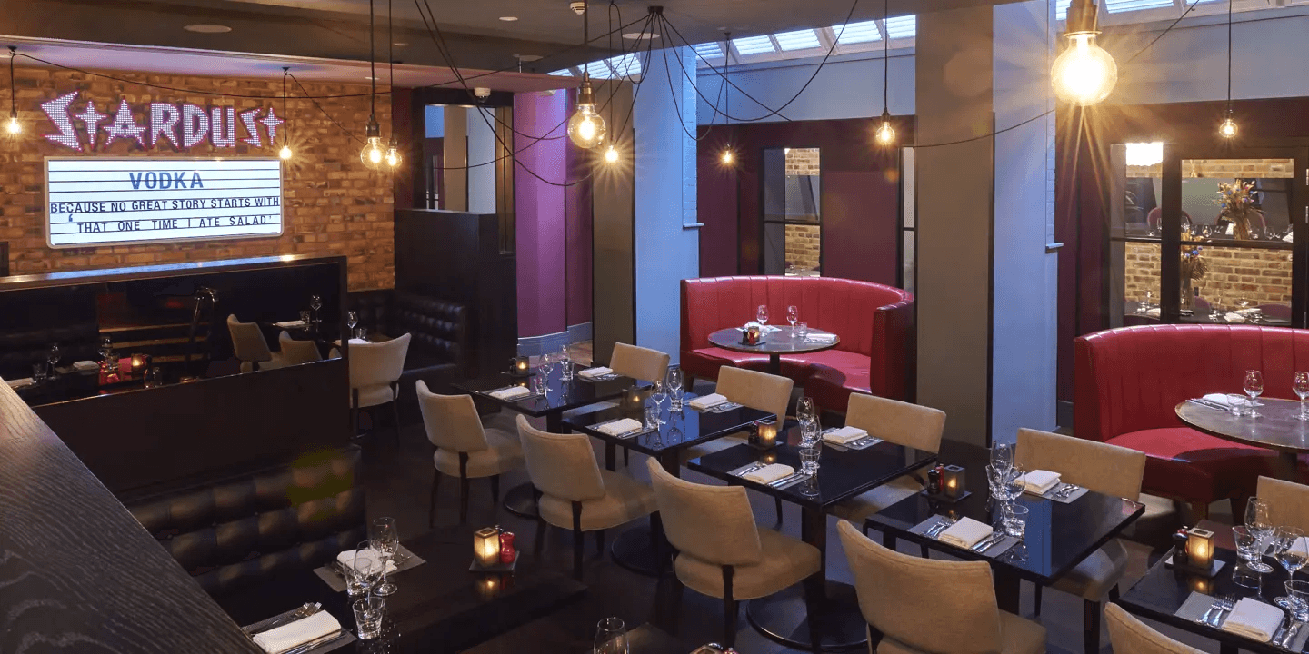 Stardust restaurant interior at Malmaison London with dark tables and red booth seating.