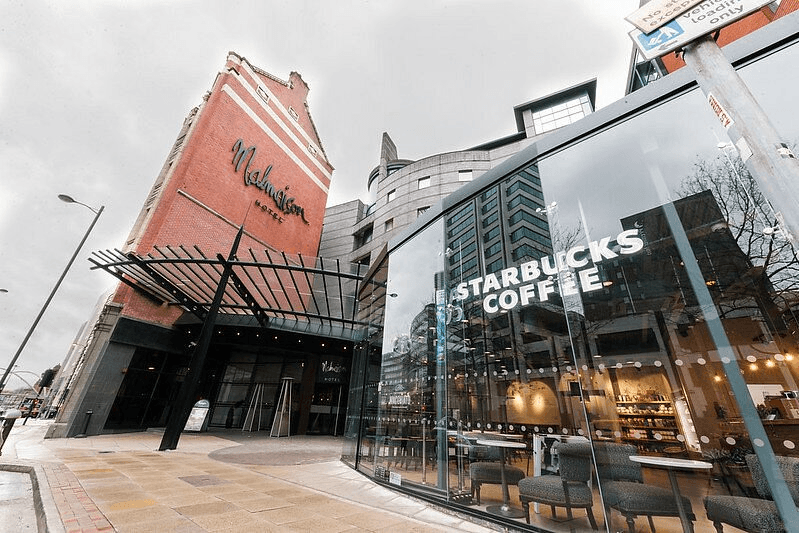 Exterior of Malmaison Manchester hotel with a Starbucks Coffee unit at street level.