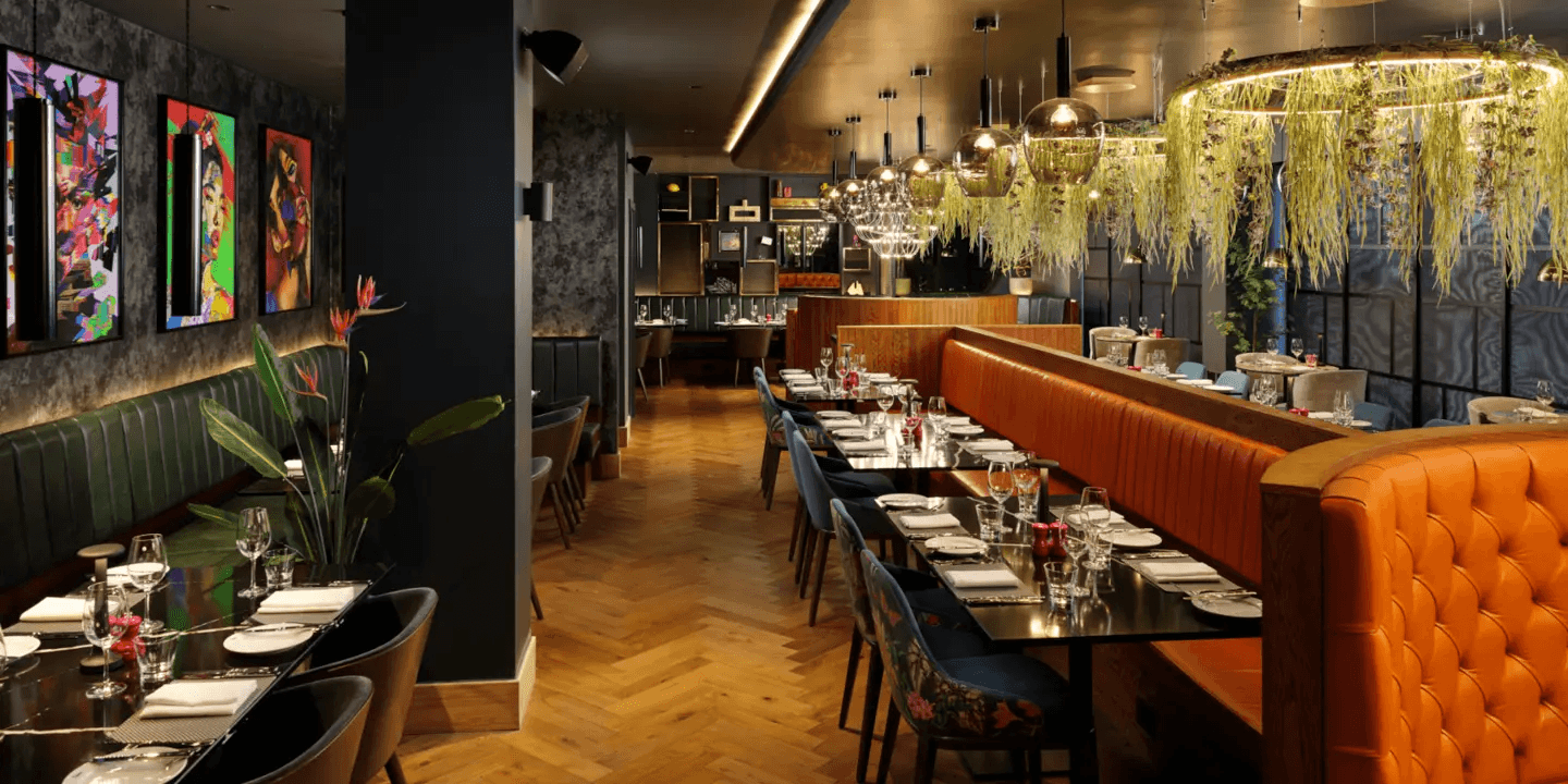 Stylish restaurant interior with tufted orange banquettes, herringbone flooring and bold pop art