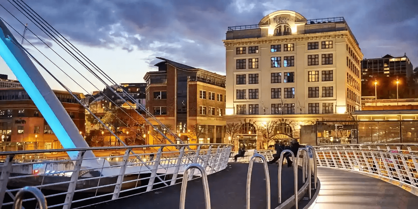 Malmaison Newcastle exterior at dusk seen from the Millennium Bridge walkway.