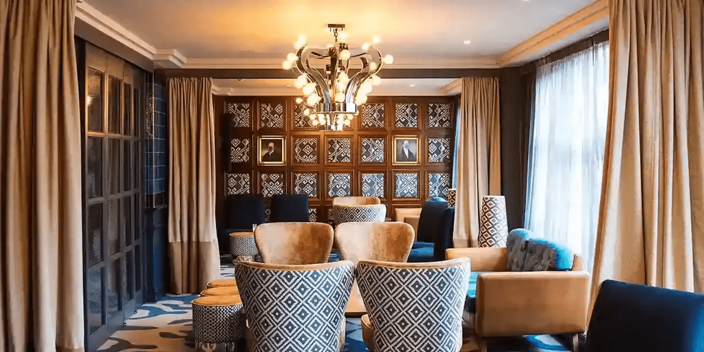 Stylish hotel lounge with patterned armchairs, a decorative chandelier and portrait paintings.