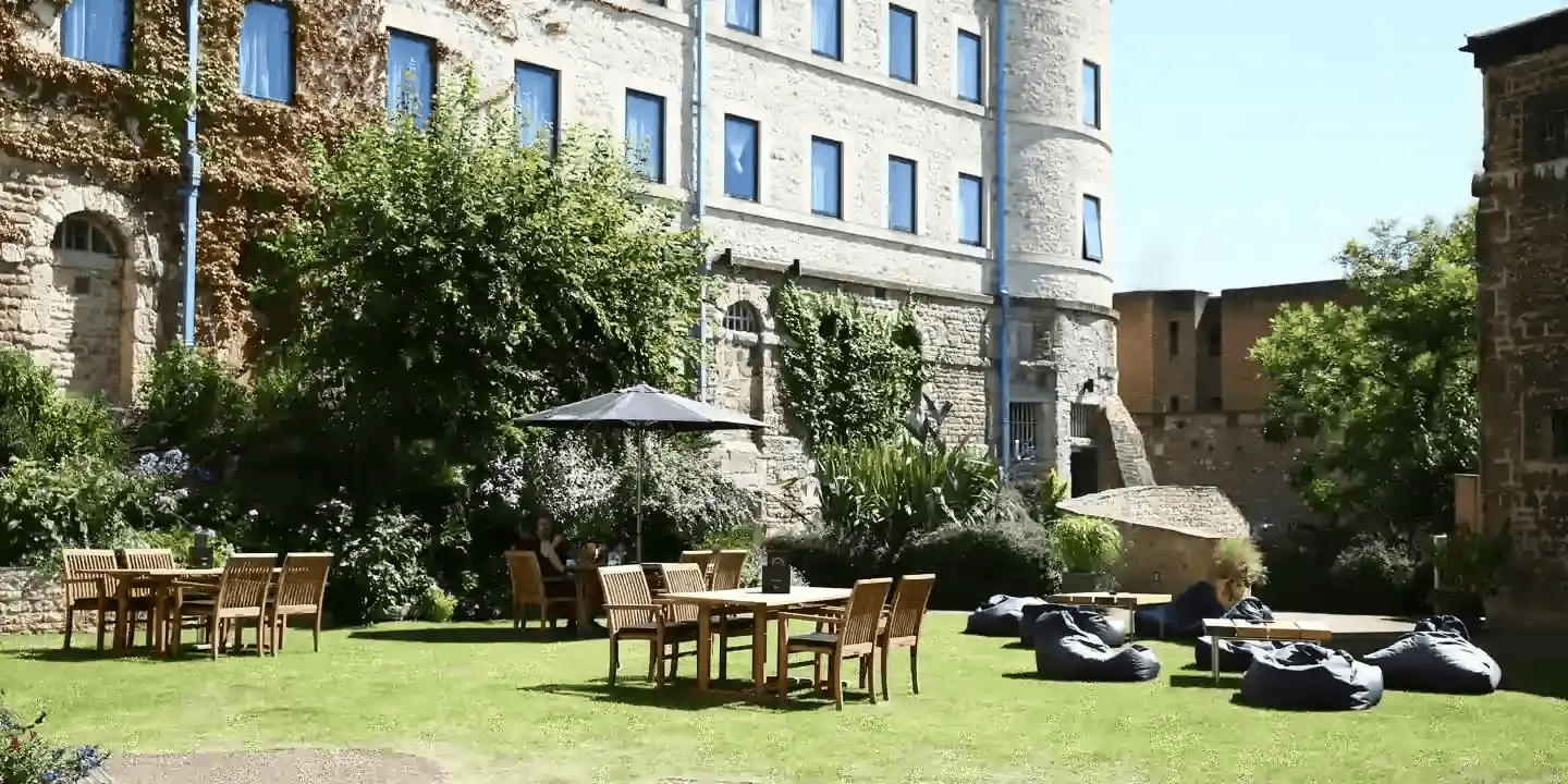 Sunny courtyard garden at Malmaison Oxford with wooden tables, chairs and bean bags.
