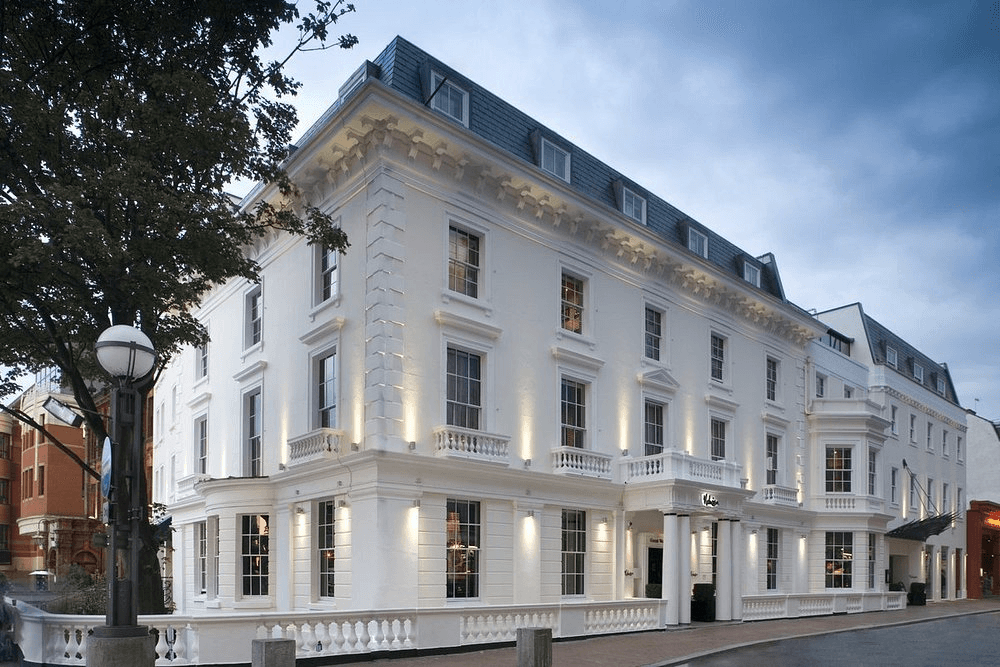 The white Georgian facade of Malmaison Reading hotel lit up at dusk.