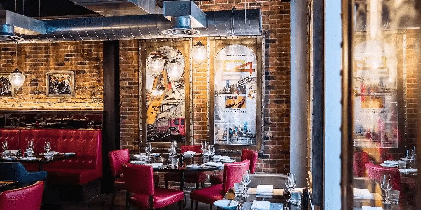 Red leather dining chairs and booths beside an exposed brick wall at Malmaison Reading.