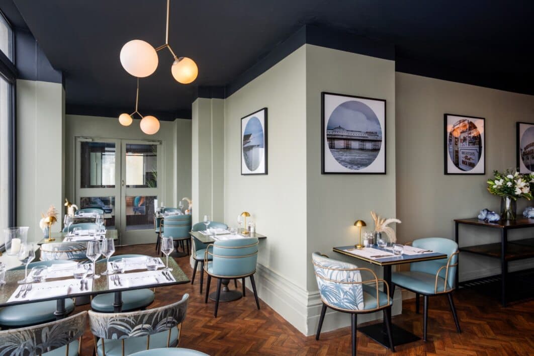 Elegant restaurant dining room with teal chairs, parquet flooring and circular Brighton artwork